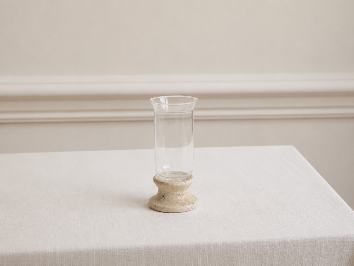 Candle holder on a white table cloth with cream wall in background with panelling