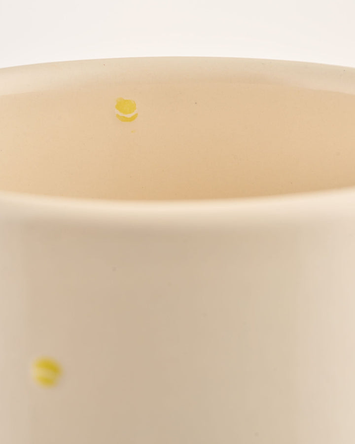 Close-up of a beige ceramic wine cooler with small yellow tennis ball illustrations