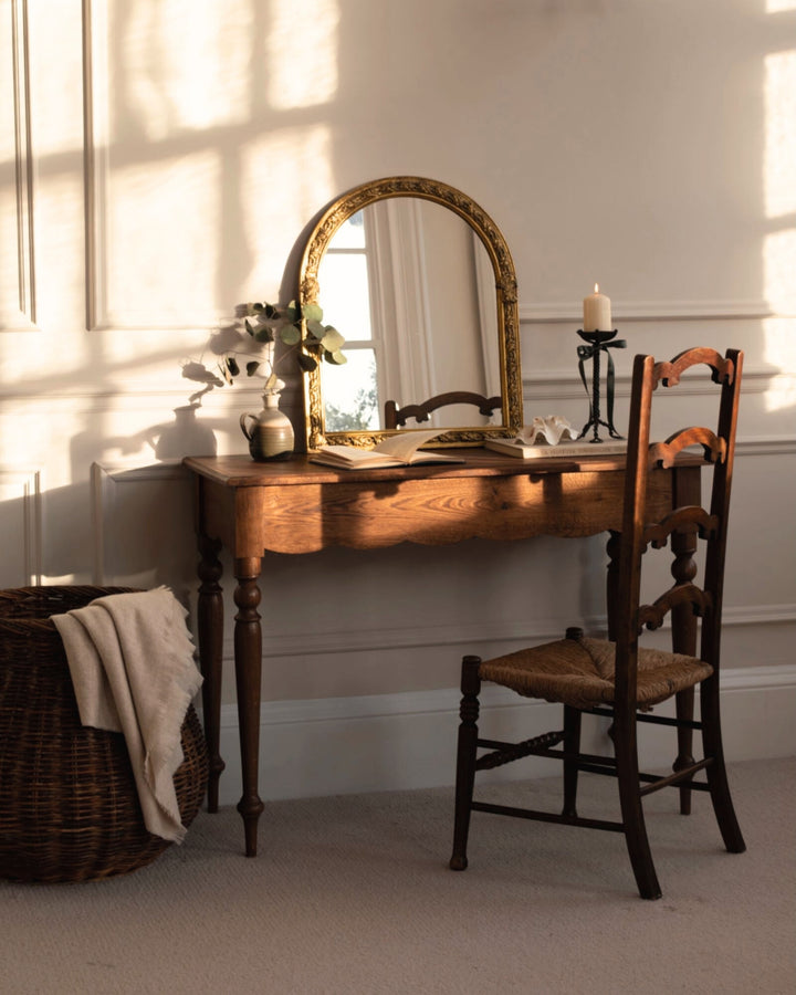 Wooden vanity table with mirror and chair in a softly lit room