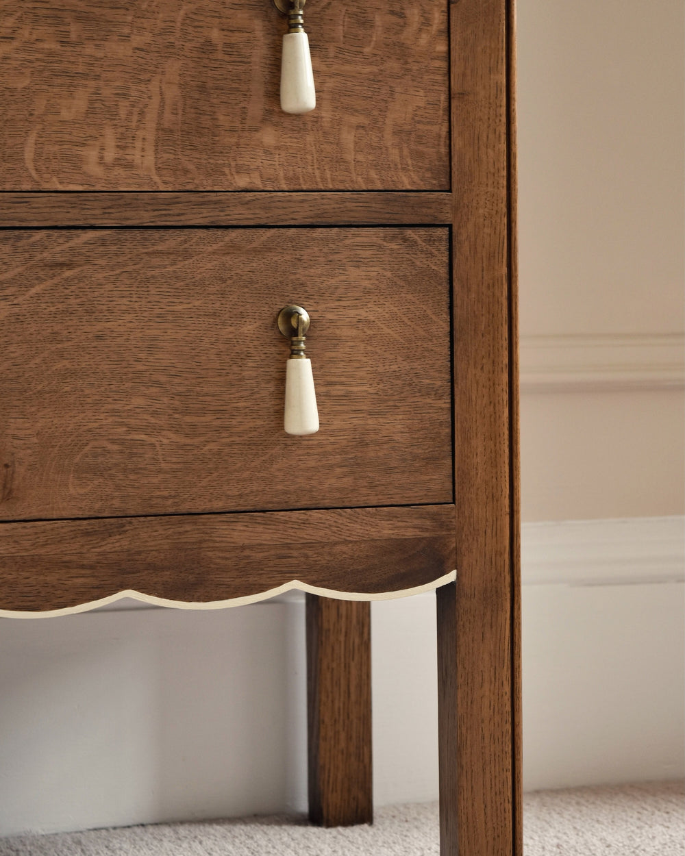Wooden bedside table with decorative knobs on a neutral background