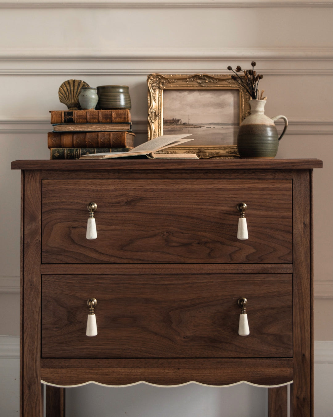 Wooden bedside table with decorative items on top against a neutral wall