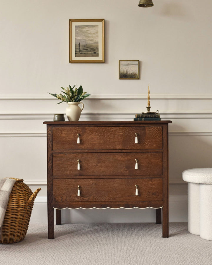 Wooden dresser with decorative items in a room with framed pictures on the wall.