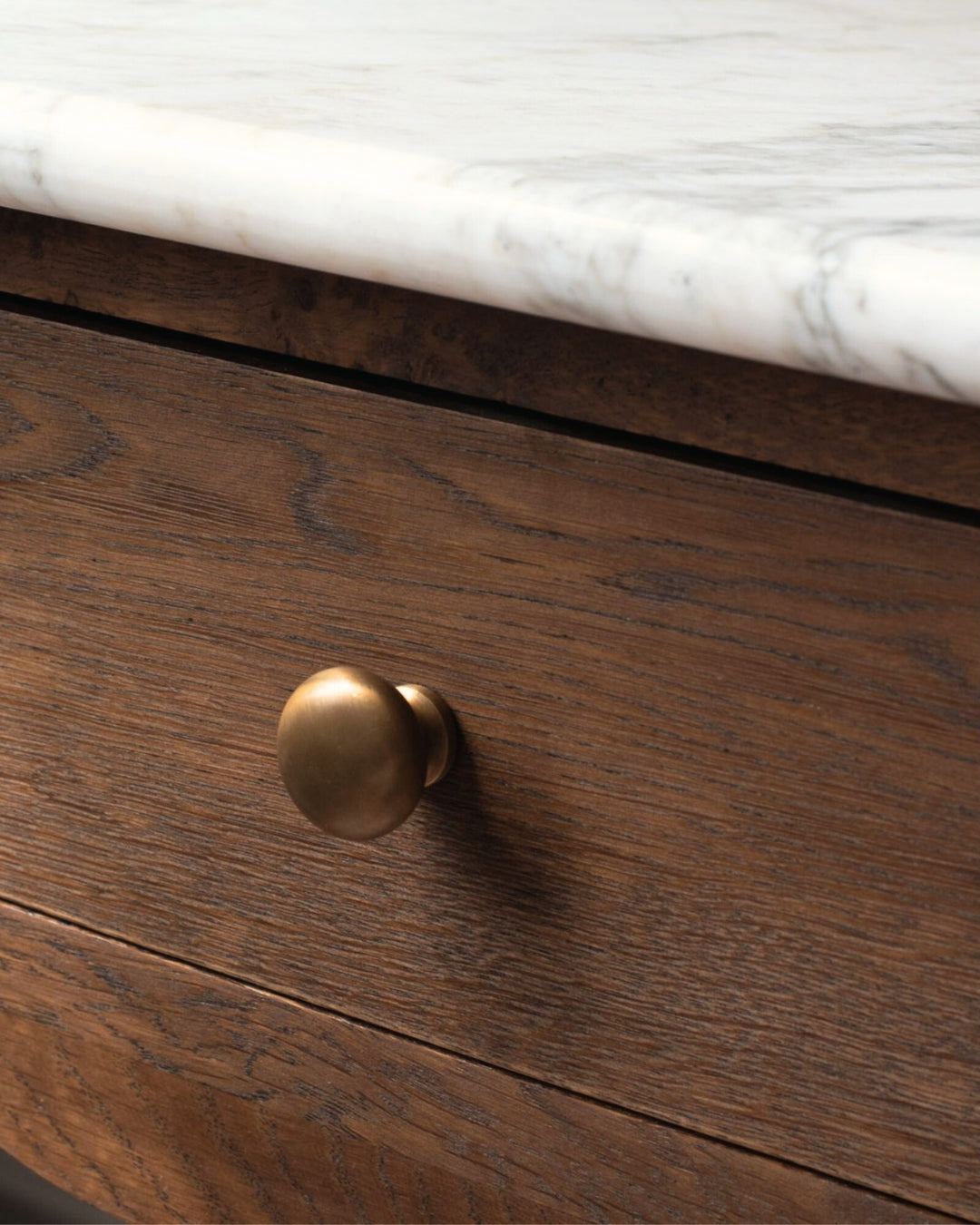 Wooden drawer with a brass knob on a marble countertop