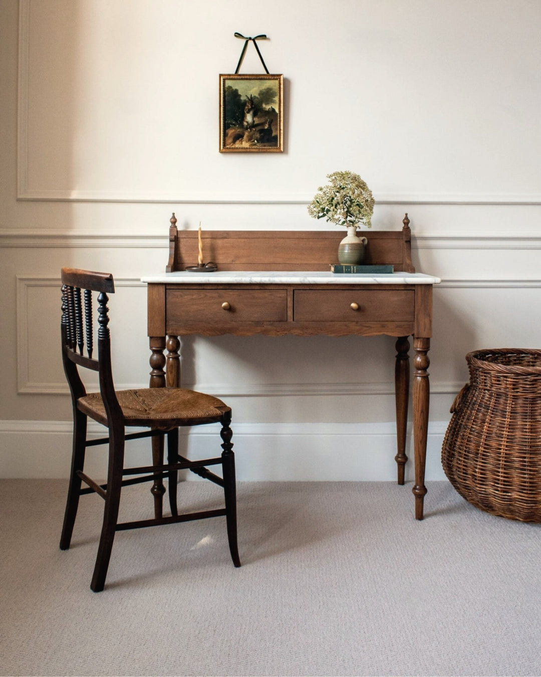 Wooden desk with chair and basket in a room with framed picture on wall