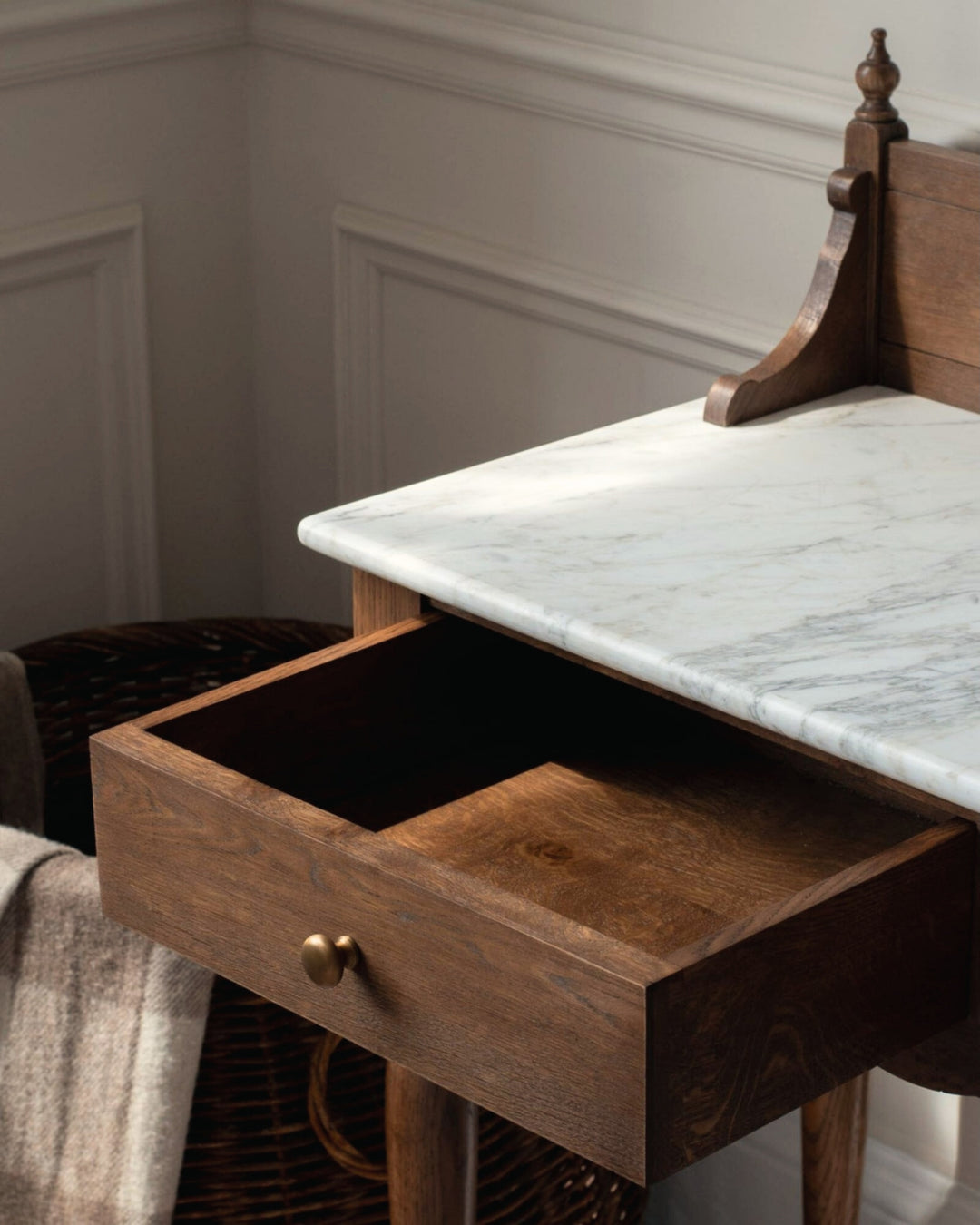 Wooden desk with marble top and open drawer in a room setting