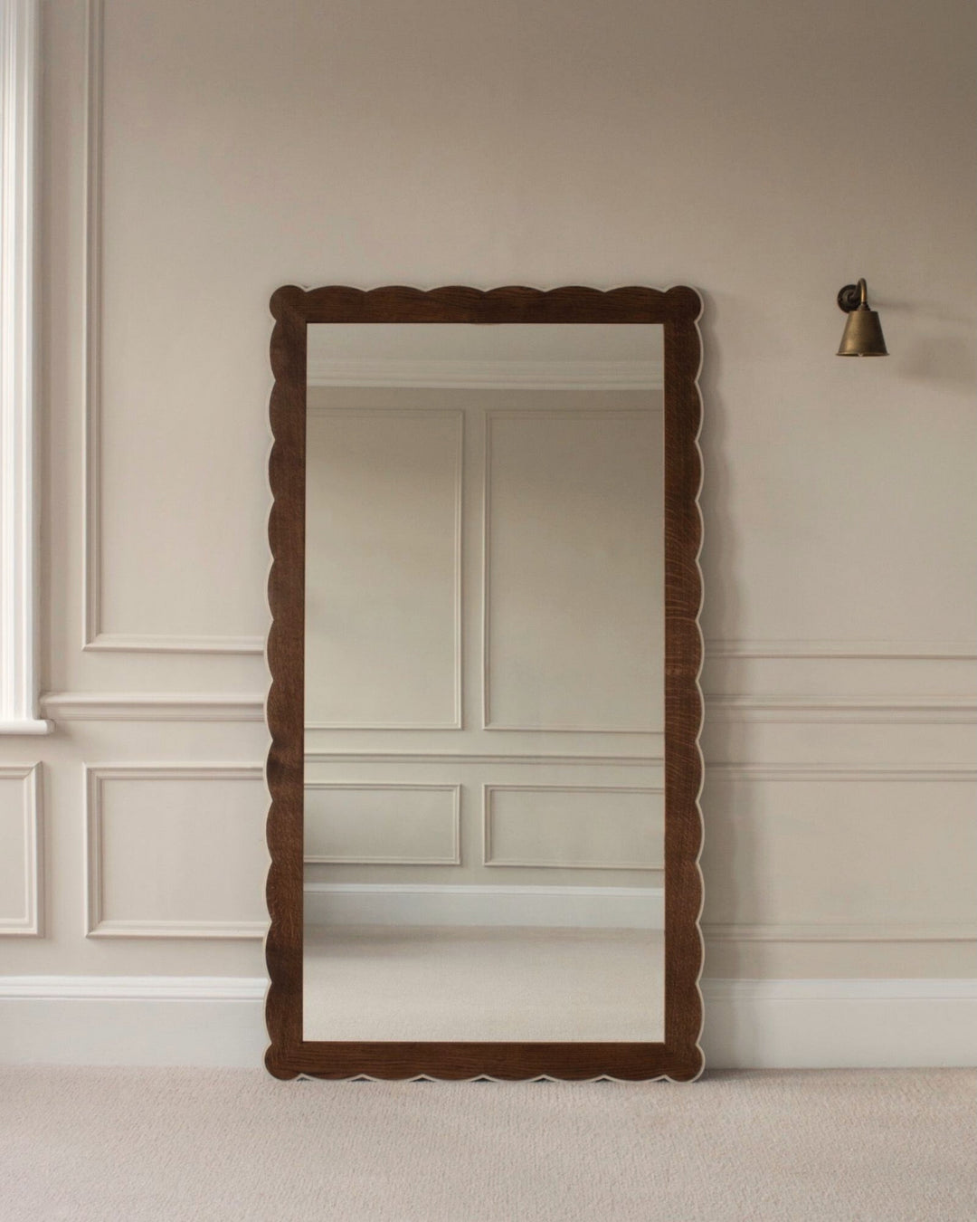 Wooden framed scalloped mirror on a beige wall