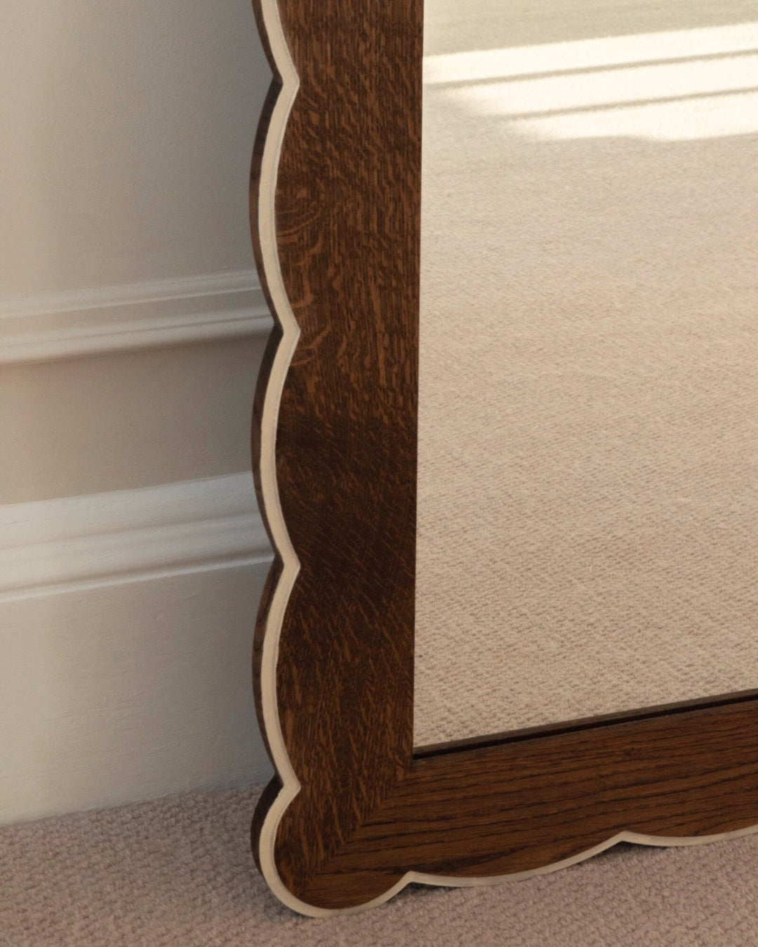 Close-up of a mirror with wooden trim and beige fabric.