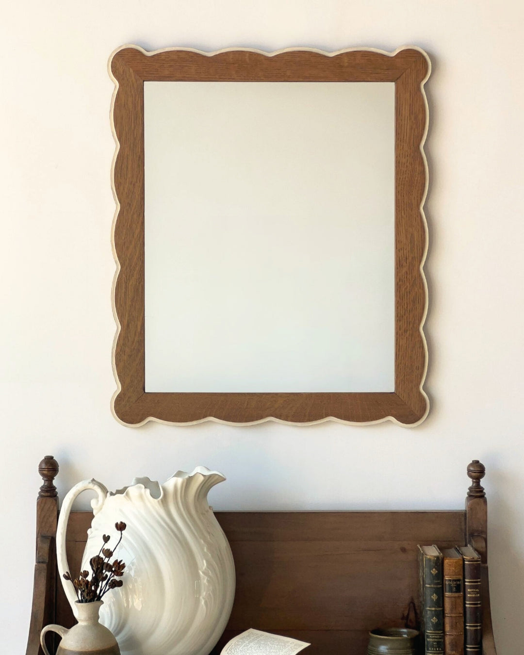 Wooden framed mirror on a wall above a wooden headboard with decorative items.
