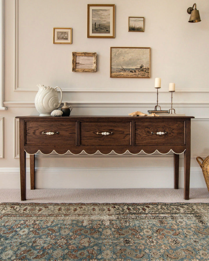 Wooden console table in a room with decorative elements and wall art.