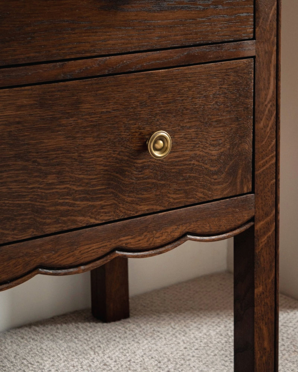 Close-up of a wooden drawer with a gold knob on a neutral background