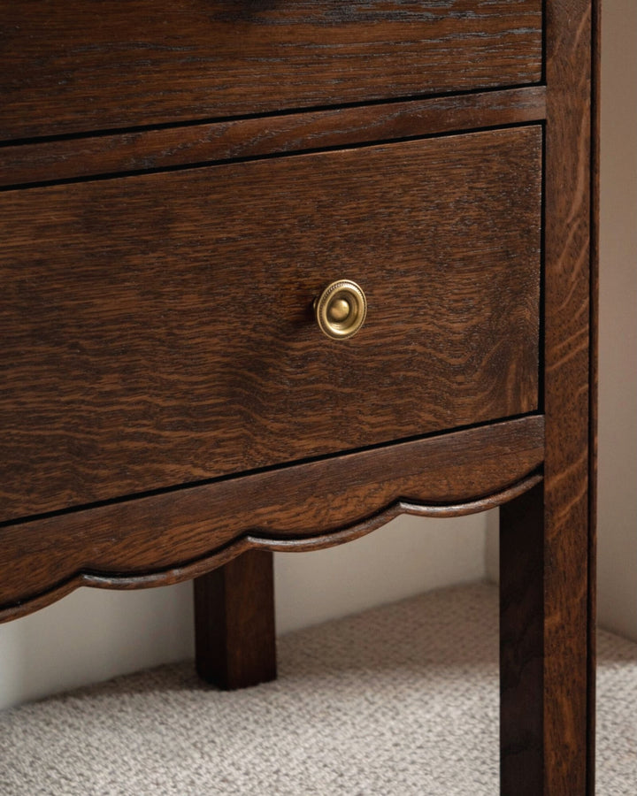 Close-up of a wooden drawer with a gold knob on a neutral background