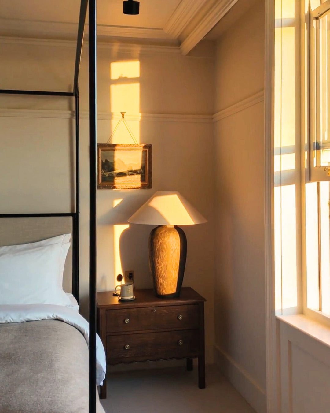 Bedroom with a wooden nightstand, lamp, and framed picture.