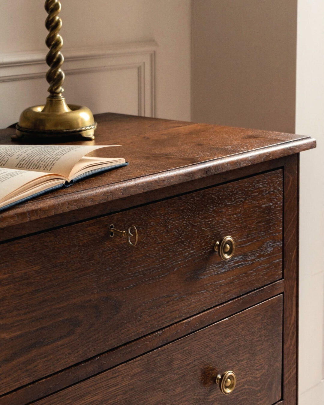 Wooden dresser with brass knobs and an open book on top