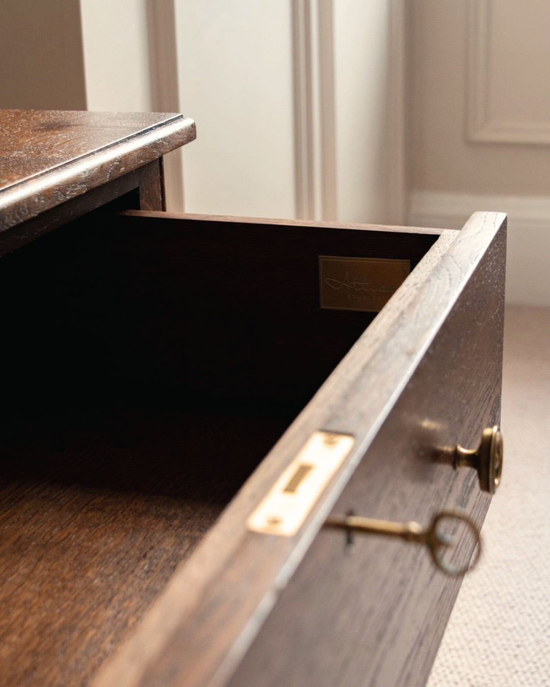 Open wooden drawer with a key on a light-colored floor.