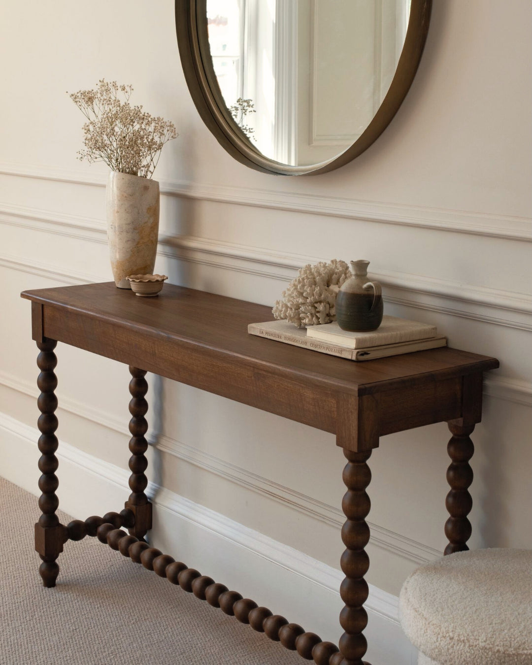 Wooden console table with decorative items against a neutral wall.