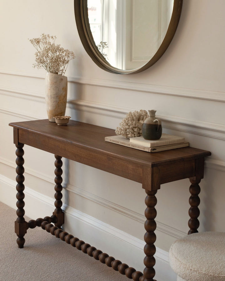 Wooden console table with decorative items against a neutral wall.