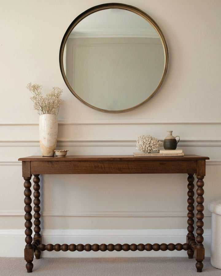 Wooden console table with decorative items against a neutral wall