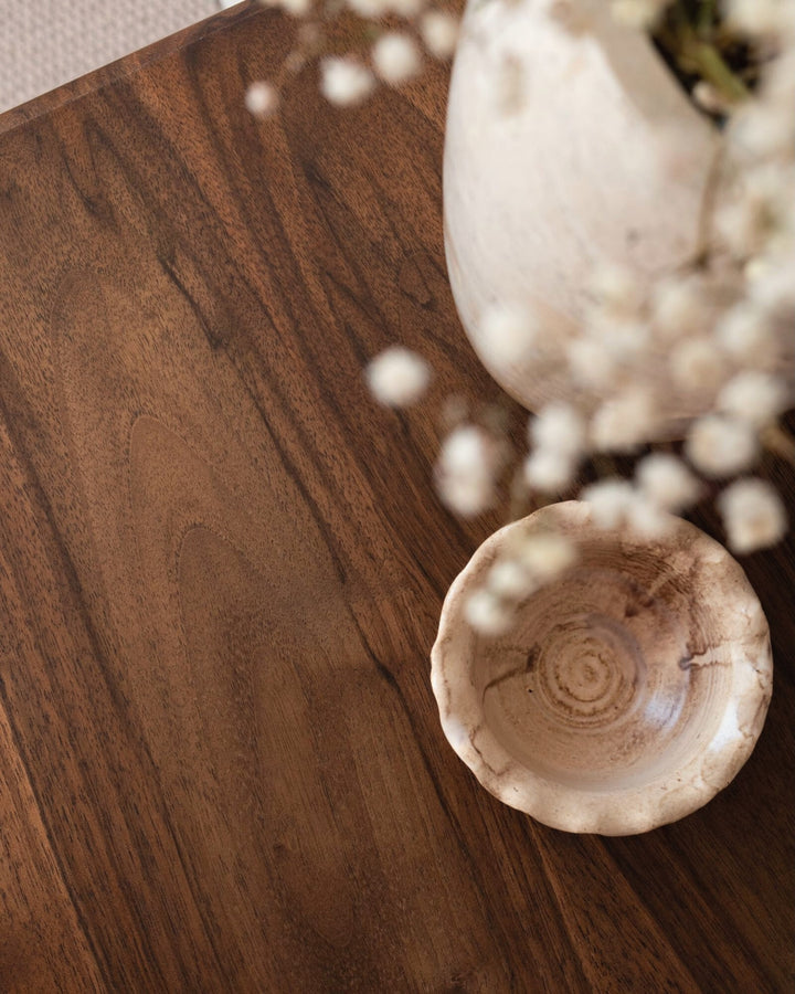 Wooden surface with a textured ceramic bowl and white flowers.