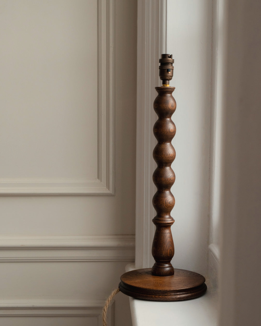 Wooden bobbin lamp base against a neutral wall