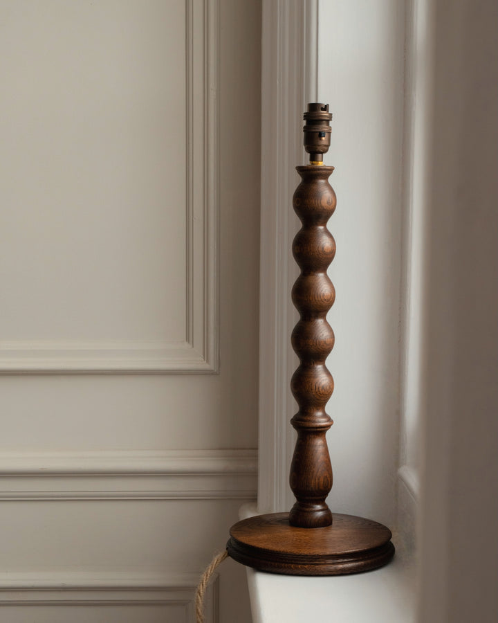 Wooden bobbin lamp base against a neutral wall