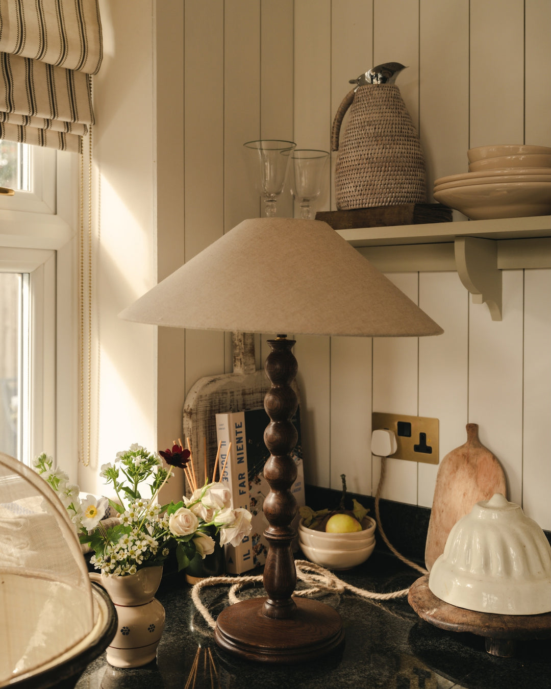 Nostalgic kitchen scene with a wooden lamp, flowers, and kitchenware.