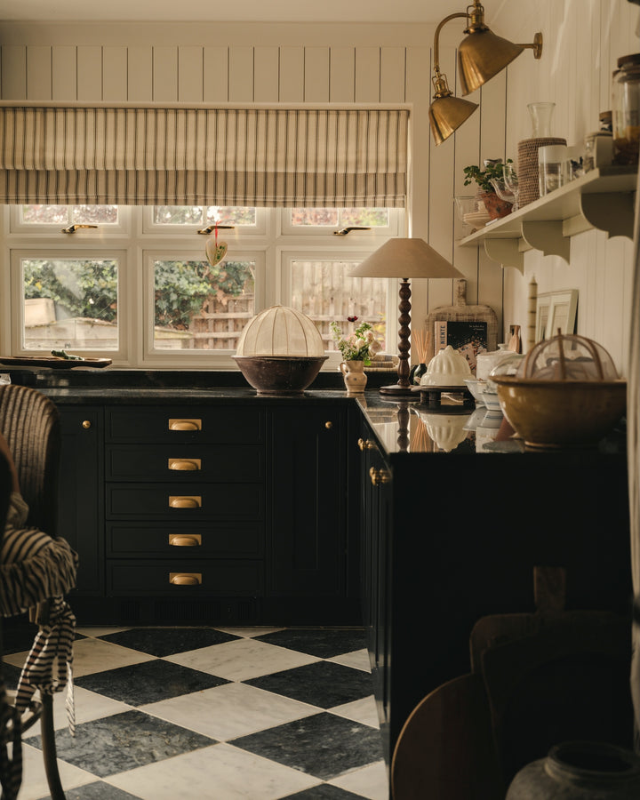 Kitchen with cabinets, checkered floor, and window view, with twooden table lamp