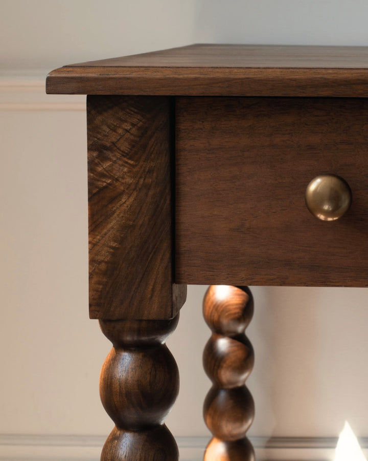 Wooden side table with bobbin legs on a neutral background