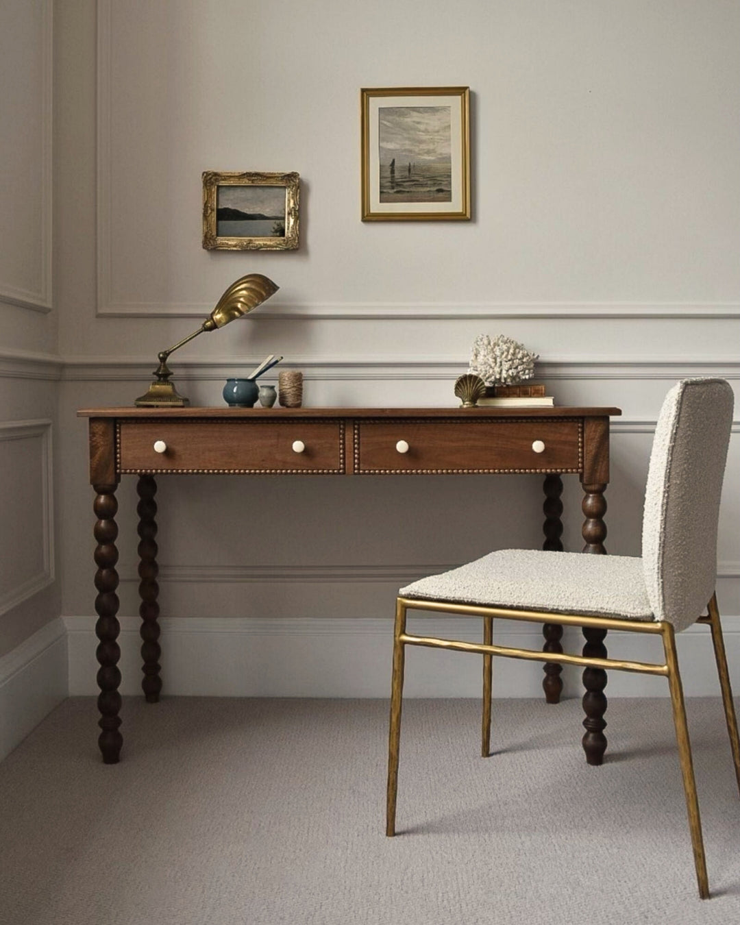 Wooden desk with decorative items and a chair in a room with framed pictures on the wall.