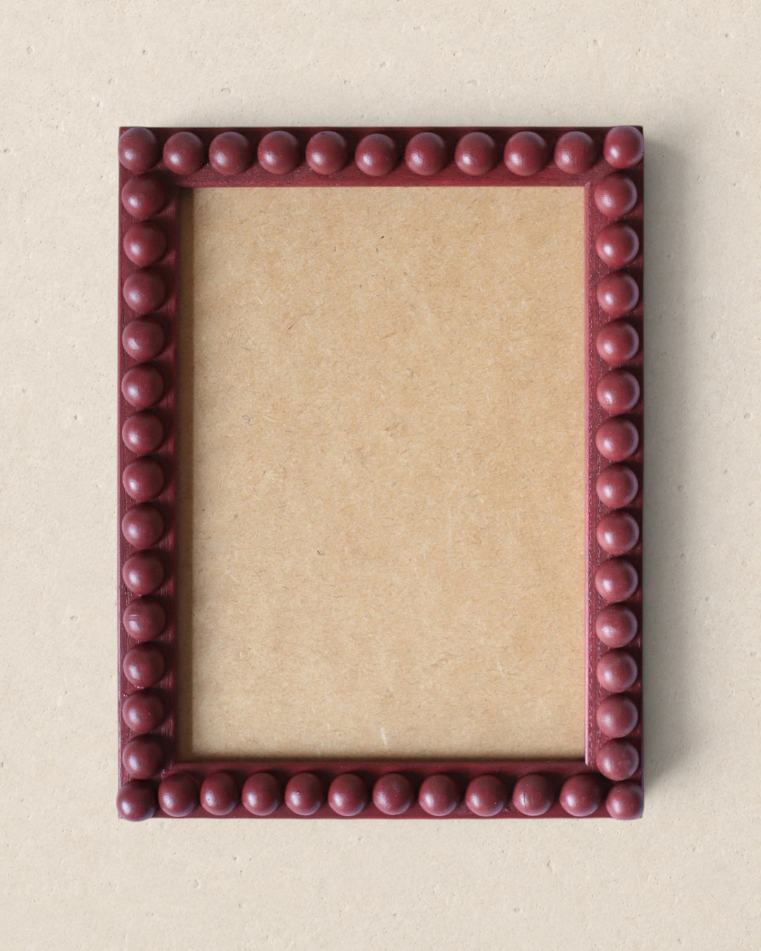 Square picture frame with a beaded border on a beige background