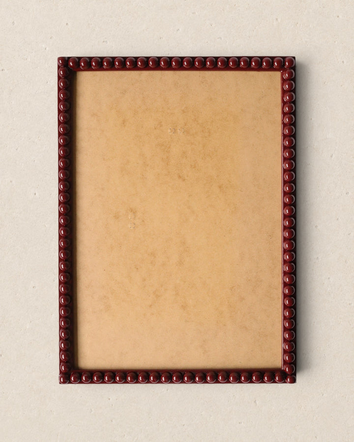 Wooden picture frame with decorative border on a beige background