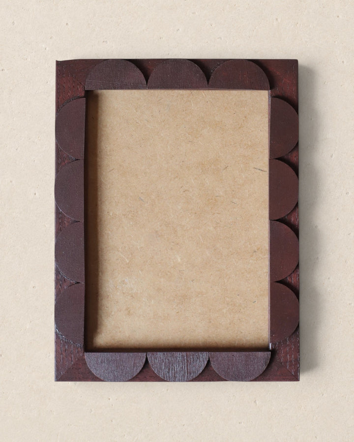 Decorative picture frame with scalloped edge on a beige background