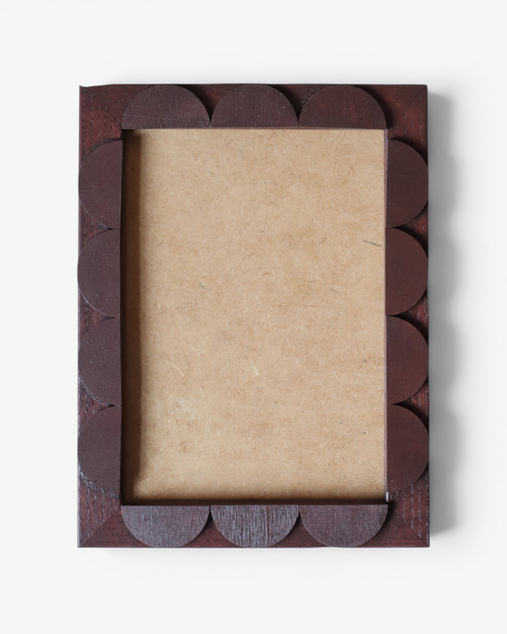 Brown decorative photo frame with scalloped edge on a white background
