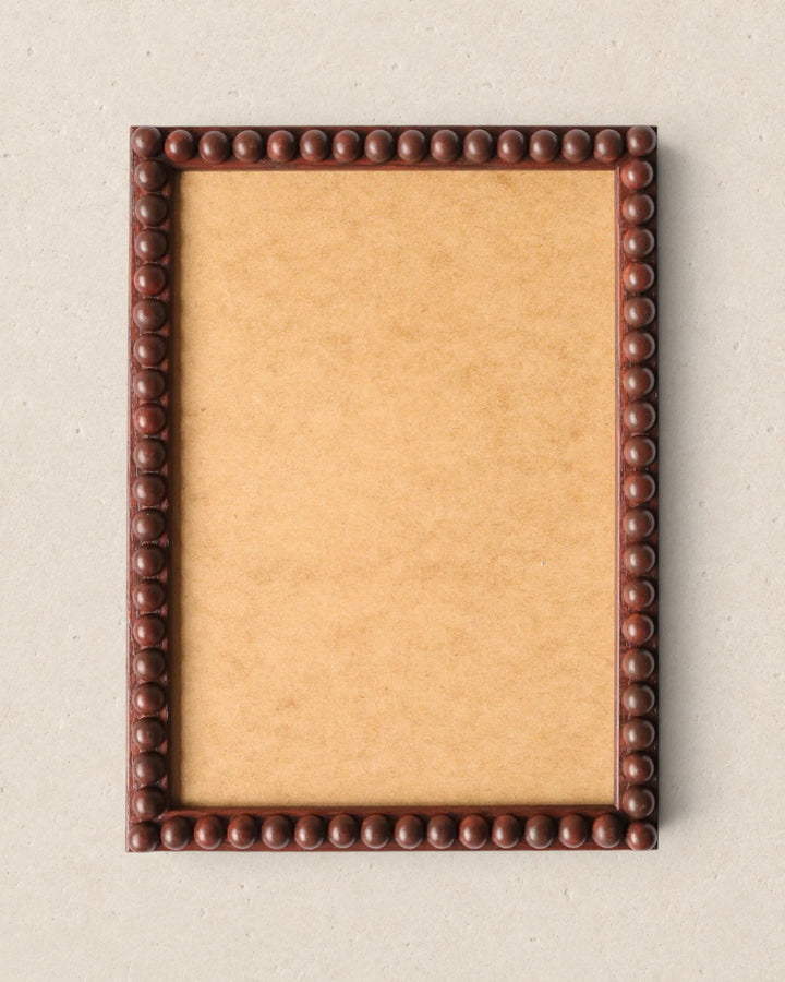 Rectangular picture frame with a decorative brown border on a beige background