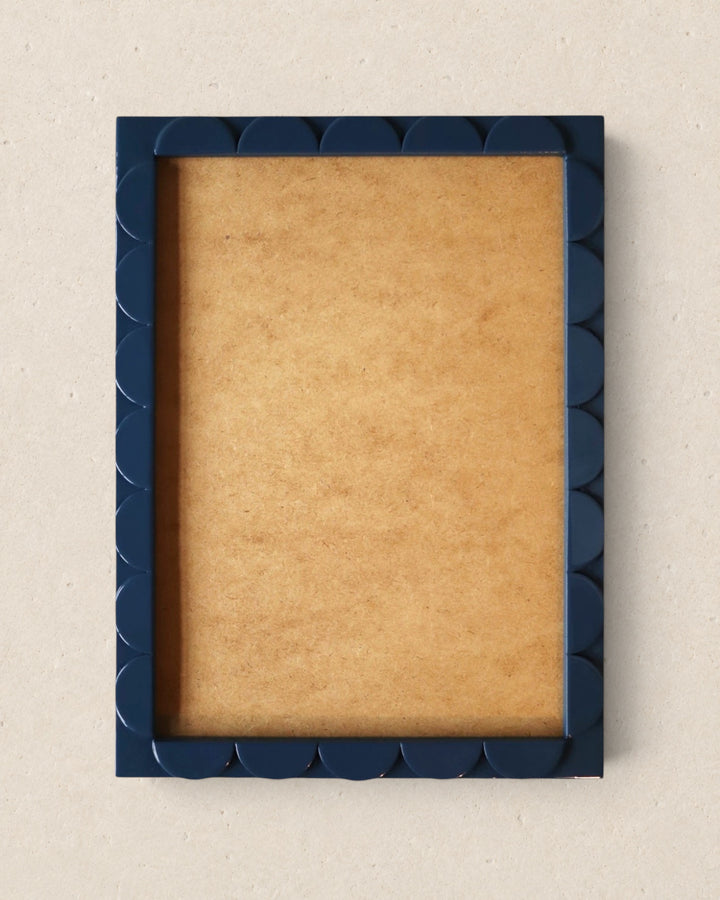 Navy blue picture frame with scalloped edge on a beige background