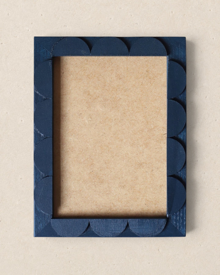 Blue scalloped picture frame on a beige background