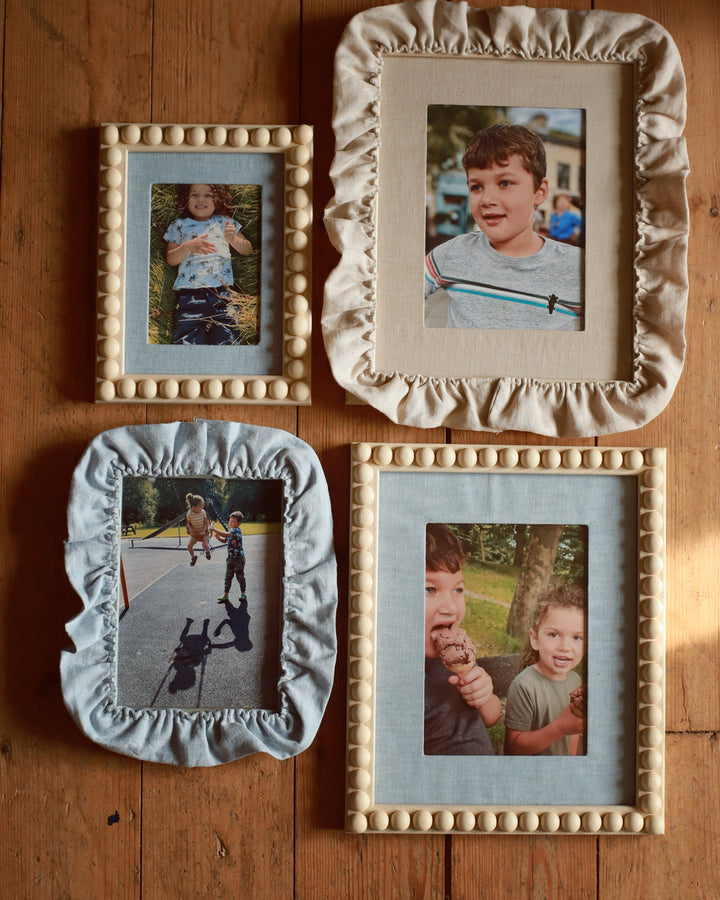 Four decorative picture frames with children's photos on a wooden surface