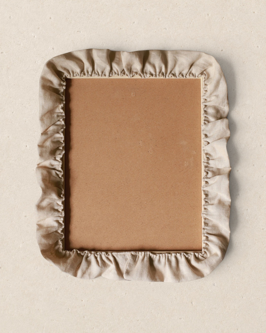 Rectangular picture frame with a beige fabric cover on a beige background