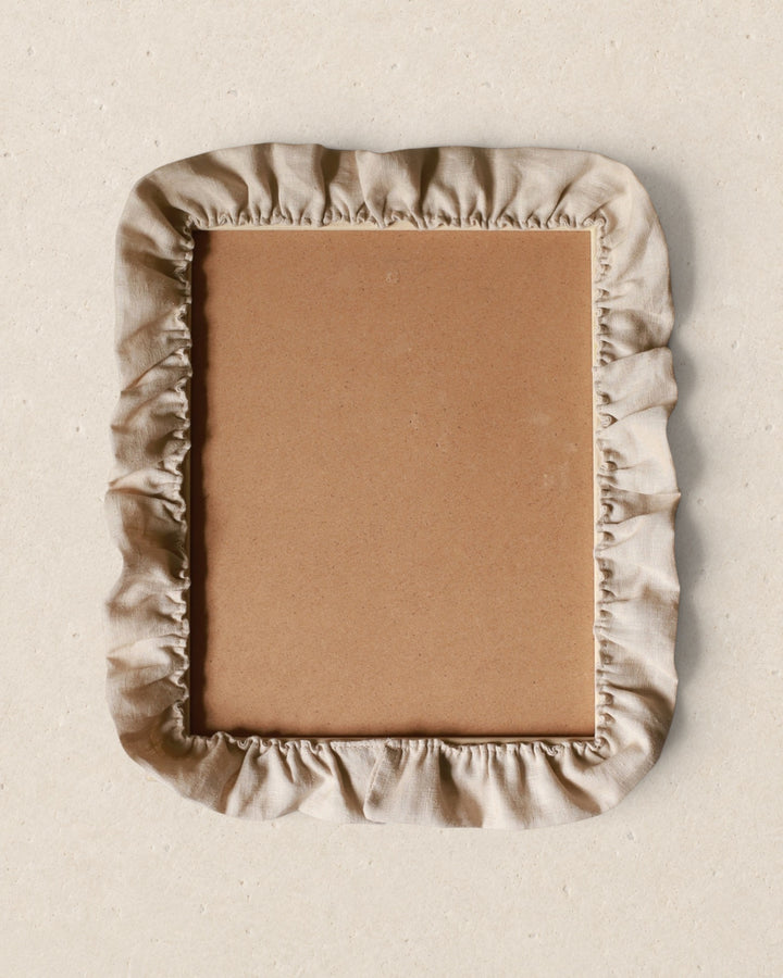 Rectangular picture frame with a beige fabric cover on a beige background