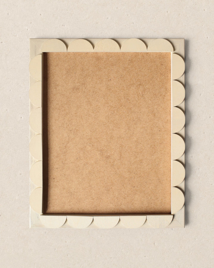 Decorative picture frame with scalloped edge on a beige background