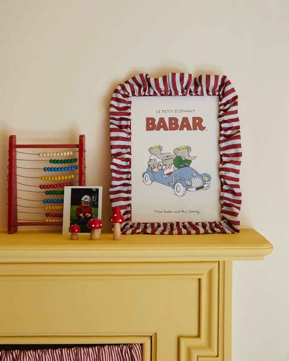Framed picture of 'Babar' with a red and white striped border on a yellow surface.