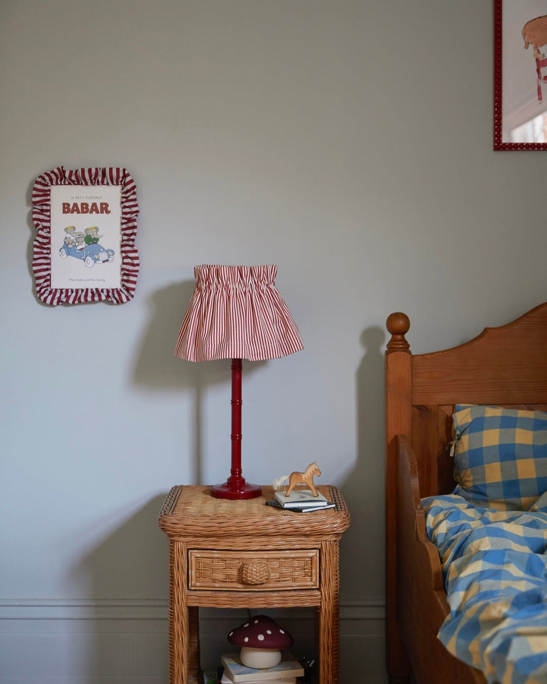 Bedroom scene with a nightstand, lamp, and bed with colorful bedding.