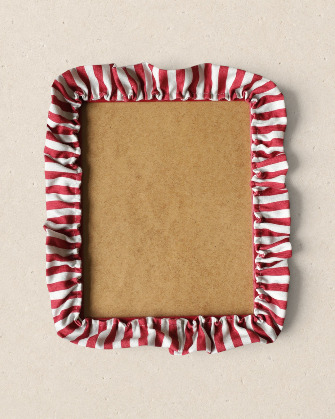 Rectangular cardboard picture frame with red and white striped border on a beige background