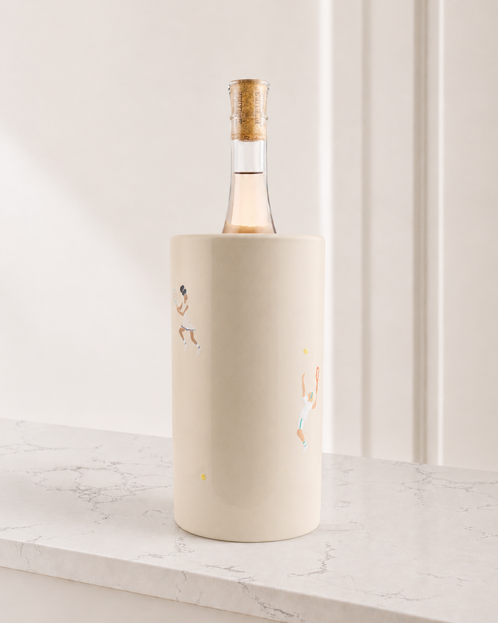 Bottle of wine in a decorative holder on a light surface with a white background