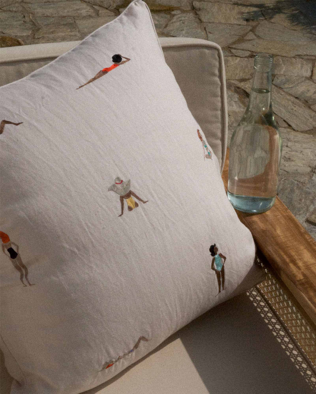 Decorative pillow with embroidered figures on a stone surface