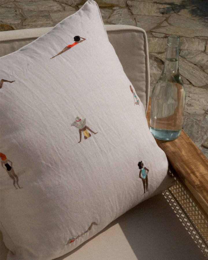 Decorative pillow with embroidered figures on a stone surface