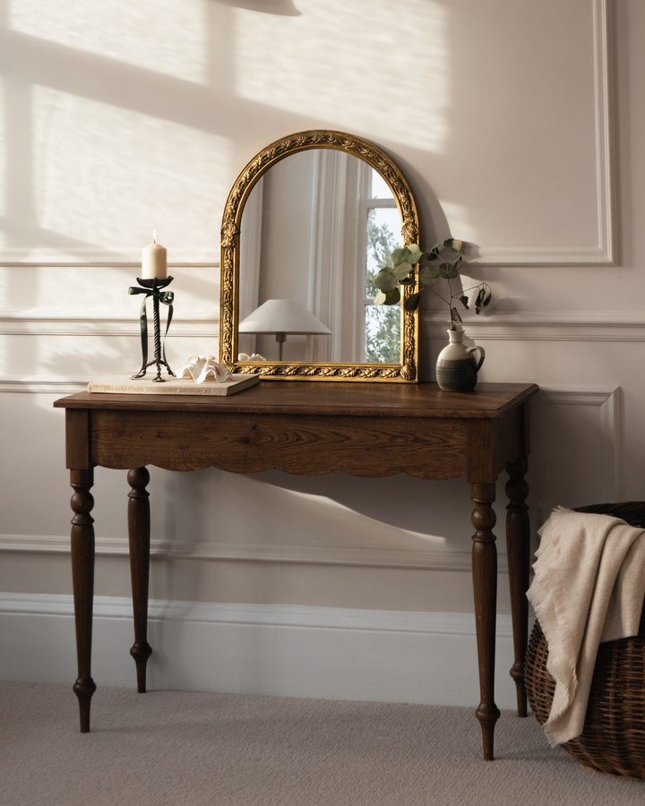 Wooden desk with mirror and candle against neutral wall