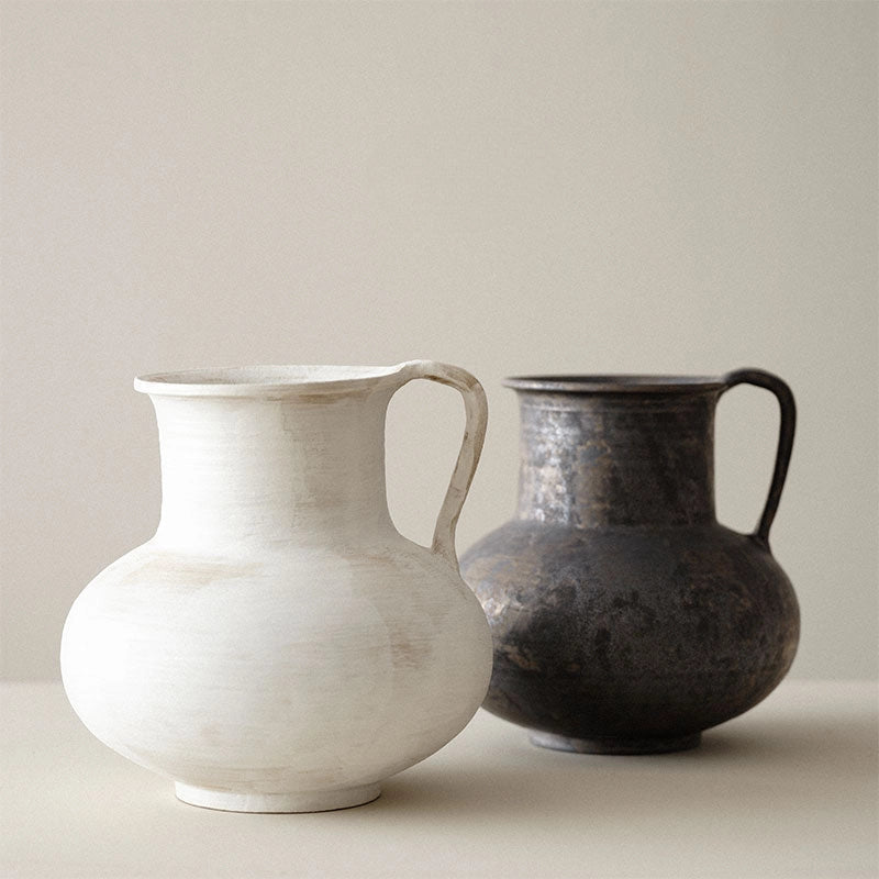 Handmade ceramic black and cream vases with curved handles, a round shape and a visible textured surface.