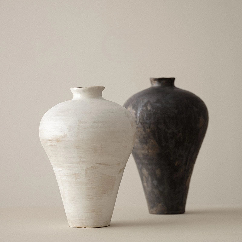 Handmade ceramic black and cream vases with a round shape and a visible textured surface.