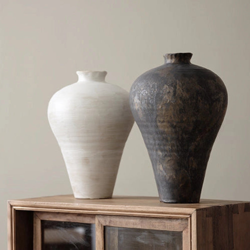 Handmade ceramic black and cream vases with a round shape and a visible textured surface.
