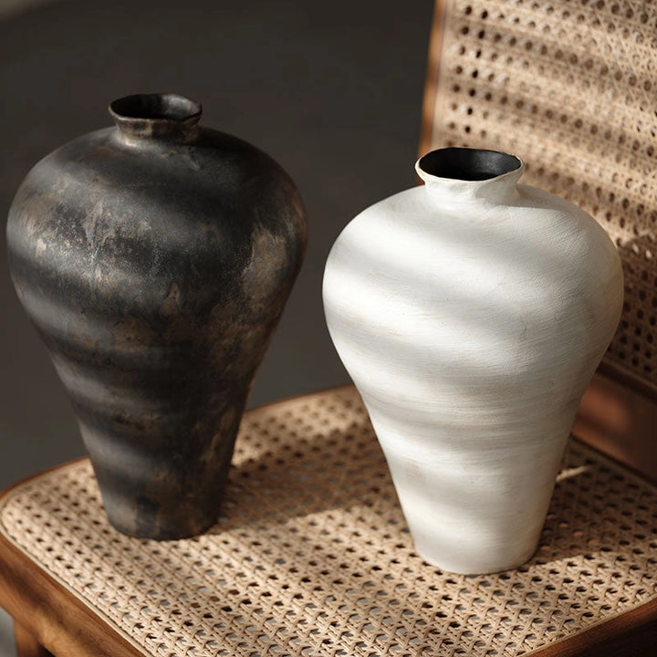 Handmade ceramic black and cream vases with a round shape and a visible textured surface.